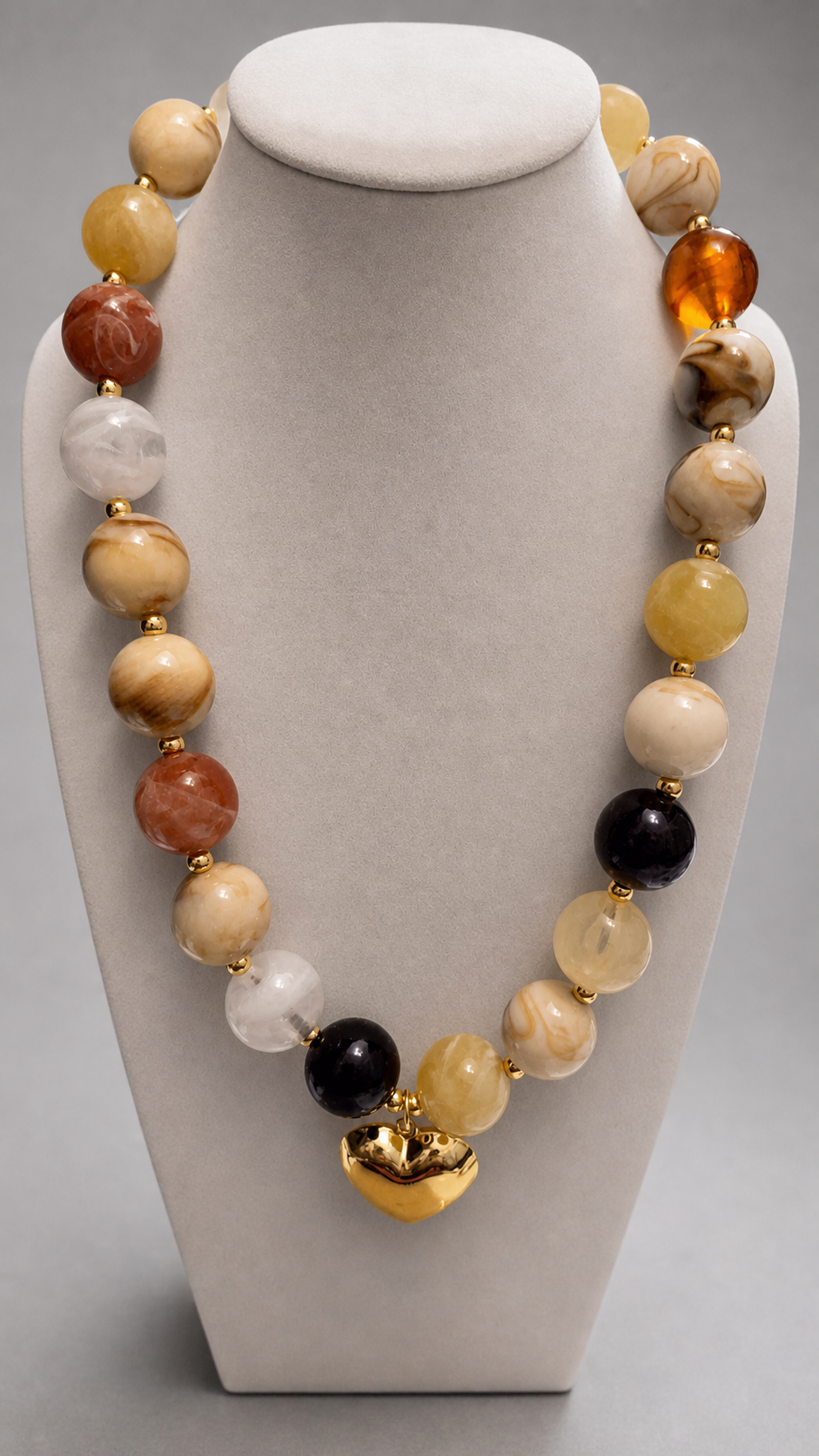 Collar de cuentas grandes en tonos tierra con corazón dorado sobre busto de exhibición