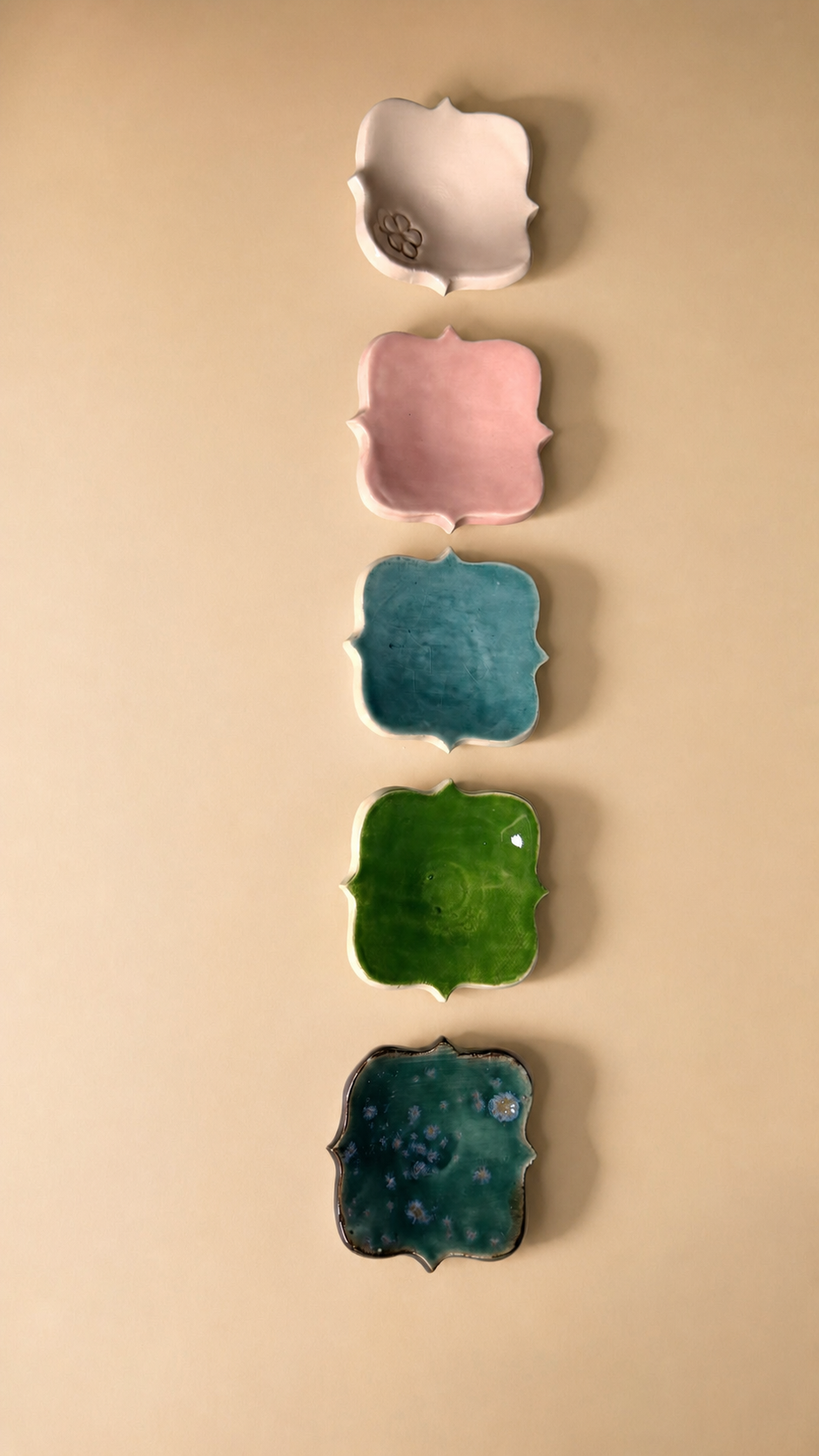 Platitos de cerámica esmaltada en cinco colores: blanco con flor, rosa, azul claro, verde y verde azulado con motas